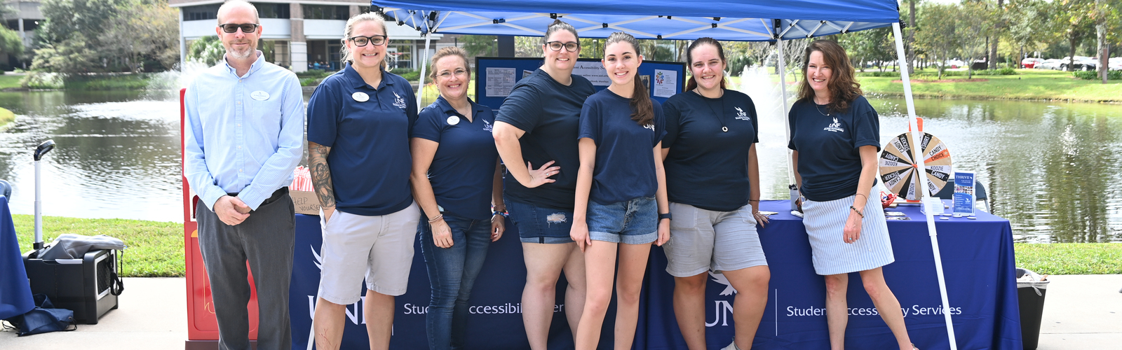Group of students standing outside by a tent and table at UNF Market Days