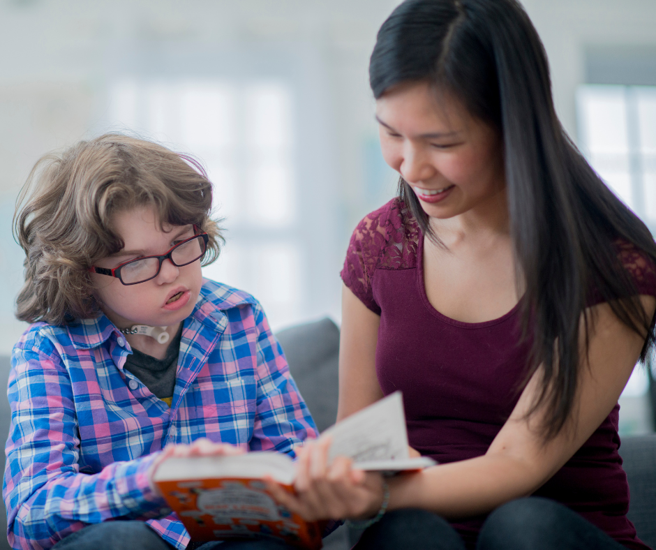 A boy reads a book with his teacher.