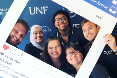 UNF students in a photo booth smiling