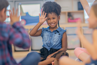 A little girl using sign language in a classroom