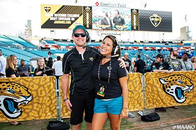 Two students at a Jacksonville Jaguars game wearing headsets on the field