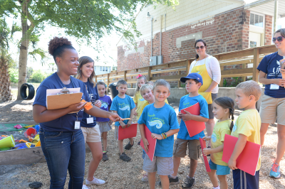 Counselors smiling with children standing outside