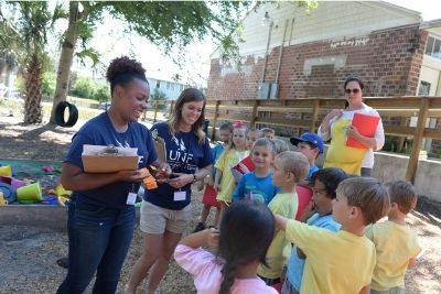 Two UNF students working with a group of children outside