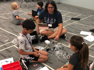 Children sitting on the floor with a teacher working on a project together