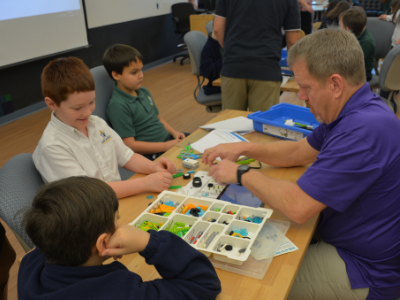 Young students sitting at a table with a teacher with arts and crafts materials