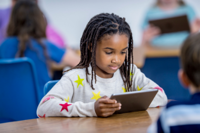 Small girl holding a tablet in a classroom