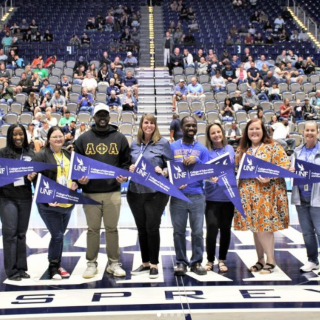 Teachers, Principals, and Assistant Principals of the year standing on the UNF Arena basketball court with UNF President Moez Limayem, COEHS Dean Dr. Jennifer Kane and Duval Superintendent Dr. Diana Greene.