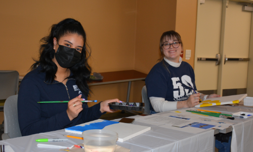 2 students painting canvas at painting party