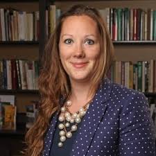 Headshot of Dr.Hannah smiling with a bookshelf as a background.