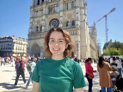 Young woman smiling in green shirt in front of older tower.