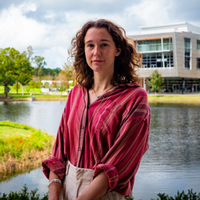 Headshot of Megan with a pond and building in the background.