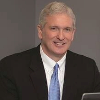 Headshot of Jay Coleman sitting in his office table