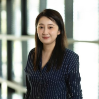 Headshot of Yan (Vicky) Ma, smiling with a blurred background in a building indoor  