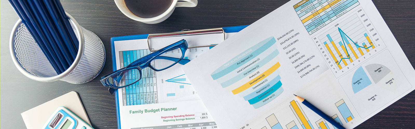 desk with charts pencils, calculator and glasses