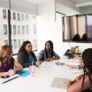A group of women in business attire talking sitting at a conference table