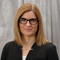 A headshot of Amy Kistka smiling and wearing a black shirt and glasses.