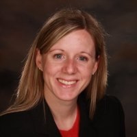 Headshot of Chelsea Carroll smiling wearing a black blazer and red shirt.