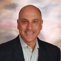 Headshot photo of Gregory Devino smiling while wearing a suit