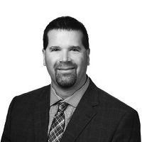 A black and white Headshot photo of Scott Batsch in a suit.