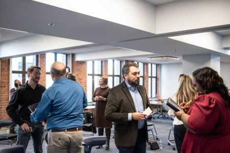 A group of people in business attire in small groups speaking with each other