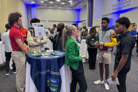 group of students gathered around enterprise holdings table