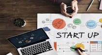 startup on paper with a computer and hands holding a coffee mug