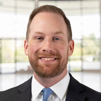 Headshot of Alex Kellison, with building window as background. 