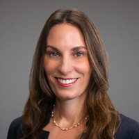 Headshot of Julie Fagan smiling, with a gray background. 