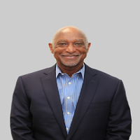 Headshot of Jim Stallings wearing a black blazer and blue shirt with light gray background