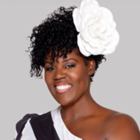 Headshot of Alexis Lior with a white flower in her hair and black and white one shoulder shirt