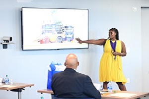 Woman in yellow dress presenting tv presenting slide with man in suit sitting and listening