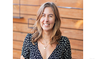 Headshot of Brianna K wearing a black shirt with white dots