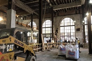 Photo of a construction site with bags, machinery and people