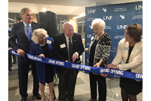 3 women and 2 men in business attire standing next to grand opening ribbon at UNF event