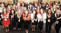 Numerous women posing at Women's Day conference in business attire