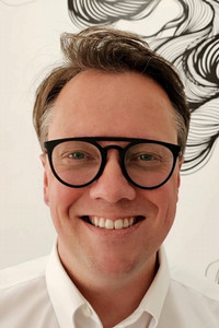 Person in white shirt before wall with abstract black line art.