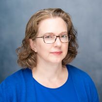 Headshot of Dr. Madeline Zavodny with a grey and white background