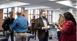 A group of people in business attire in small groups speaking with each other