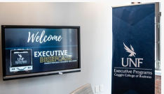  tv with welcome executive briefcase and a sign with UNF logo and executive programs coggin college of business