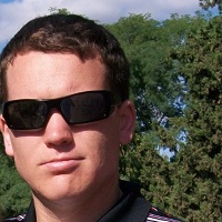 Headshot of Shane Wilson with sunglasses on and trees in the background.