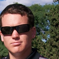 Headshot of Shane Wilson with sunglasses on and trees in the background.