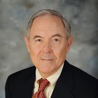 Headshot of earle traynham with a suit and red tie with gray background