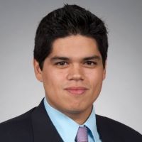 Headshot of sebastian marentes wearing a suit and purple tie with gray background