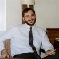 Bruce Fortado sitting down and smiling while wearing a collared shirt and tie
