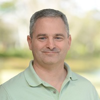 Headshot of C. Brain Flynn smiling and wearing a green shirt