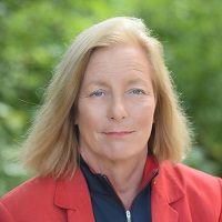 Head of Cheryl A Van Deusen wearing an orange blazer and black shirt