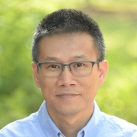 Headshot of Justin Zhang with glasses and a light blue collared shirt