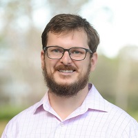 Headshot of Matthew Leon wearing glasses and a light pink collared shirt