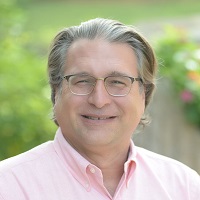 Headshot of Paul A. Fadil wearing glasses and a light pink collared shirt