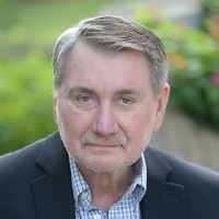 Headshot of Steven A. Williamson wearing a black blazer and blue checkered shirt